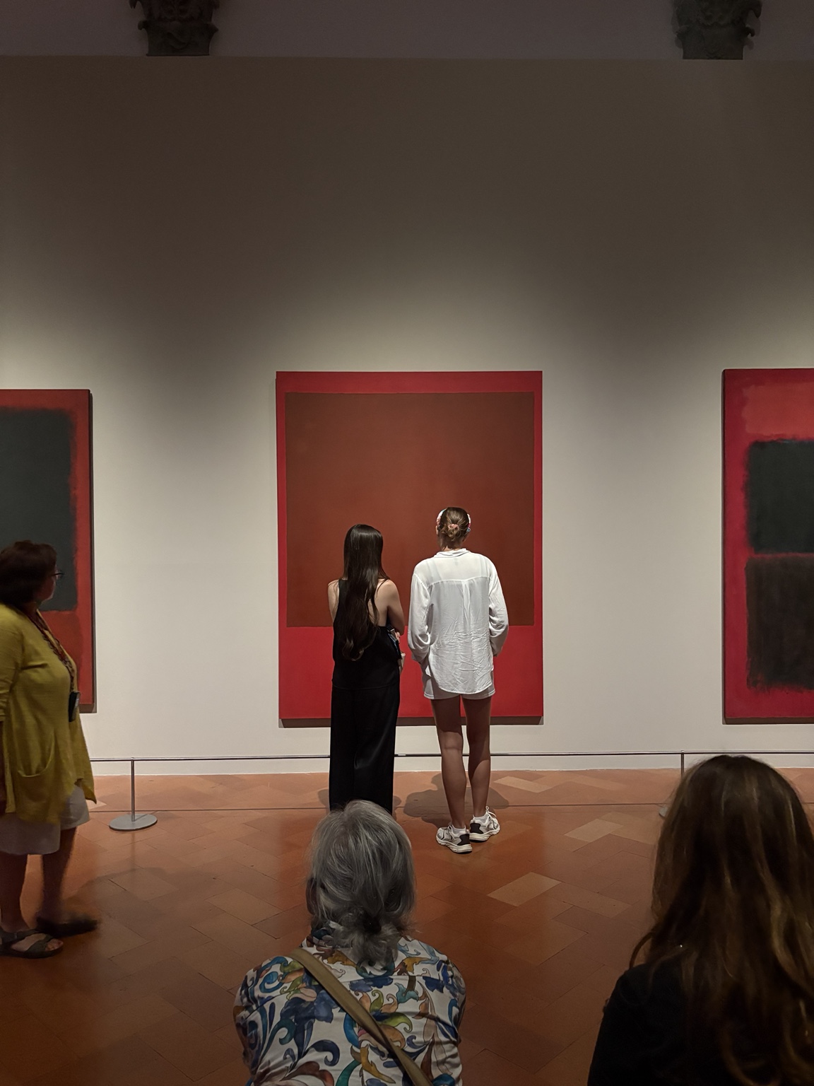 Museum visitors facing red paintings
