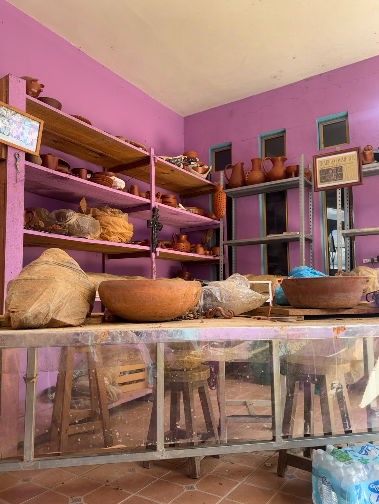 Terracotta vessels and tools inside a pink Oaxaca workshop